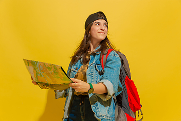 Image showing Portrait of a cheerful young caucasian tourist girl isolated on yellow background