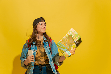 Image showing Portrait of a cheerful young caucasian tourist girl isolated on yellow background