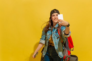 Image showing Portrait of a cheerful young caucasian tourist girl isolated on yellow background