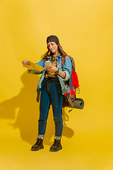 Image showing Portrait of a cheerful young caucasian tourist girl isolated on yellow background