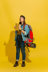 Image showing Portrait of a cheerful young caucasian tourist girl isolated on yellow background