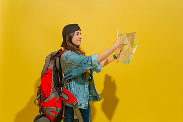 Image showing Portrait of a cheerful young caucasian tourist girl isolated on yellow background