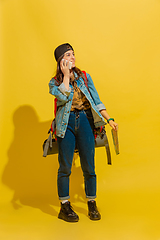 Image showing Portrait of a cheerful young caucasian tourist girl isolated on yellow background