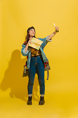 Image showing Portrait of a cheerful young caucasian tourist girl isolated on yellow background