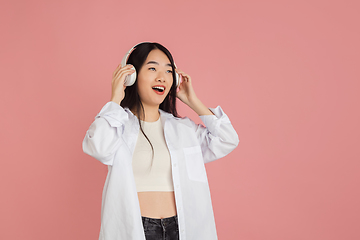 Image showing Asian young woman\'s portrait on pink studio background. Concept of human emotions, facial expression, youth, sales, ad.