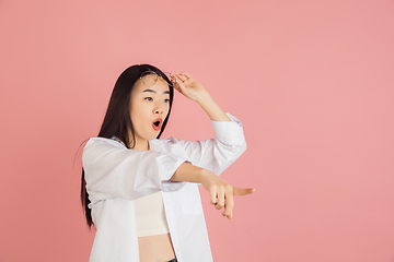 Image showing Asian young woman\'s portrait on pink studio background. Concept of human emotions, facial expression, youth, sales, ad.