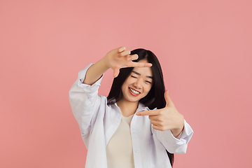 Image showing Asian young woman\'s portrait on pink studio background. Concept of human emotions, facial expression, youth, sales, ad.