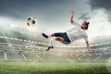 Image showing Male soccer, football player catching ball in jump at the stadium during sport match on dark sky background