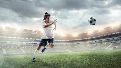 Image showing Male soccer, football player catching ball in jump at the stadium during sport match on dark sky background