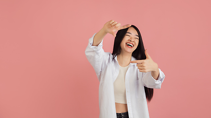 Image showing Asian young woman\'s portrait on pink studio background. Concept of human emotions, facial expression, youth, sales, ad.