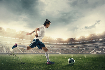 Image showing Male soccer, football player catching ball in jump at the stadium during sport match on dark sky background