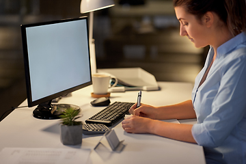 Image showing businesswoman writing to notebook at night office