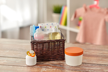 Image showing baby things in basket on wooden table at home