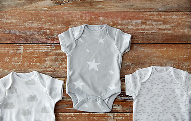 Image showing baby clothes set of bodysuits on wooden table