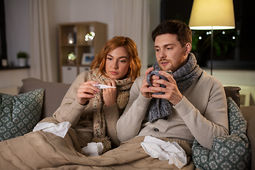 Image showing sick couple with thermometer and tea at home