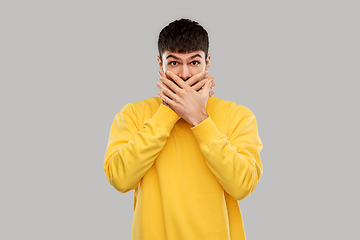 Image showing shocked young man covering his mouth with hands