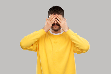 Image showing man in yellow sweatshirt closing his eyes by hands