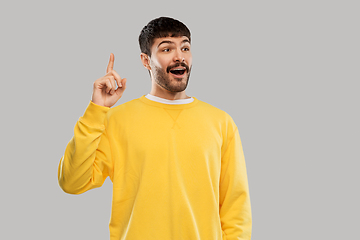 Image showing young man showing one finger in yellow sweatshirt