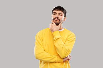 Image showing thinking young man in yellow sweatshirt