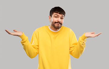 Image showing confused man in yellow sweatshirt shrugging