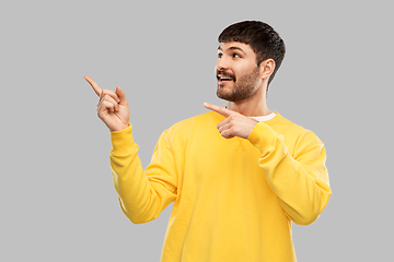 Image showing smiling man pointing fingers to something