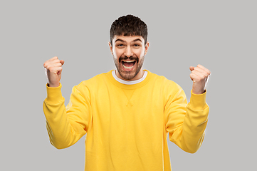 Image showing happy man in yellow sweatshirt celebrating victory