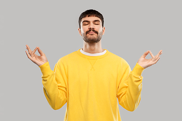 Image showing young man in yellow sweatshirt meditating