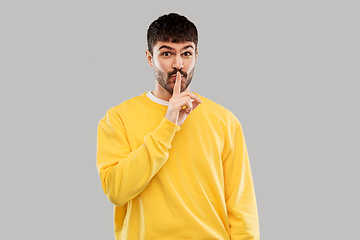 Image showing young man making hush gesture with finger on lips