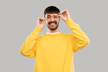 Image showing goofy young man in glasses and yellow sweatshirt