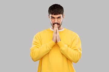 Image showing man in yellow sweatshirt praying or giving thanks