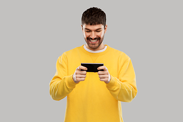 Image showing happy smiling young man with smartphone