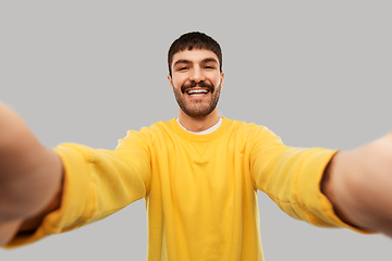 Image showing happy young man in yellow sweatshirt making selfie