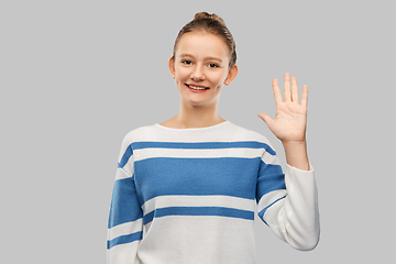 Image showing smiling teenage girl in pullover waving hand