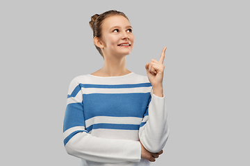 Image showing happy teenage girl in pullover pointing finger up