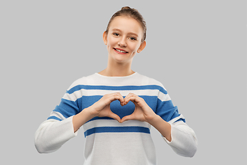 Image showing smiling teenage girl making hand heart