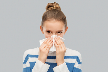 Image showing sick teenage girl blowing nose with paper tissue