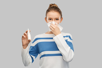 Image showing sick teenage girl with nasal spray blowing nose