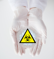 Image showing hands with test sample and boihazard caution sign