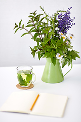 Image showing herbal tea, notebook and flowers in jug on table