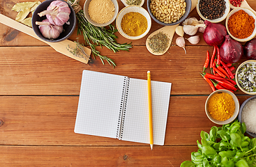 Image showing notebook with pencil among spices on wooden table