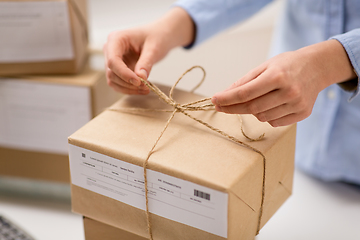 Image showing woman packing parcel and tying rope at post office