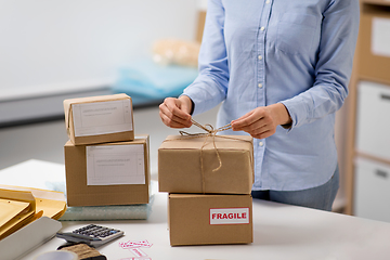 Image showing woman packing parcel and tying rope at post office