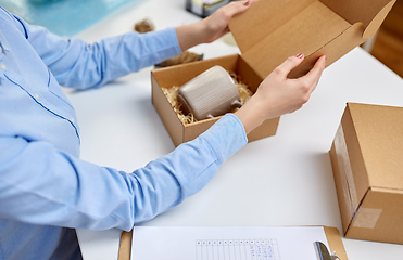 Image showing woman packing mug to parcel box at post office