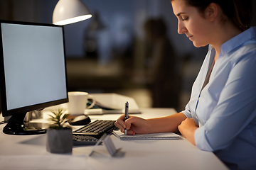 Image showing businesswoman writing to notebook at night office