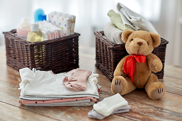 Image showing baby clothes and teddy bear toy on table at home