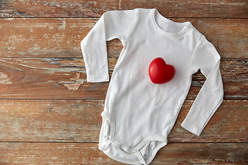 Image showing baby bodysuit with red heart toy on wooden table