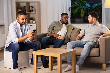 Image showing man using smartphone while friends talking at home