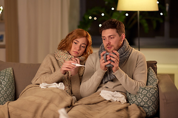 Image showing sick couple with thermometer and tea at home