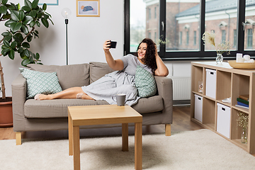 Image showing happy woman taking selfie with smartphone at home