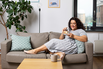 Image showing smiling young woman eating cake at home